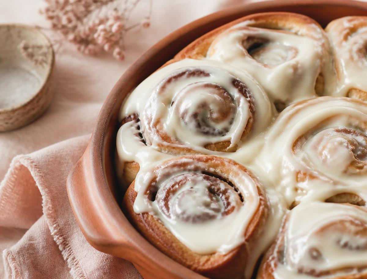 Sourdough cinnamon rolls with cream cheese frosting in a terracotta dish